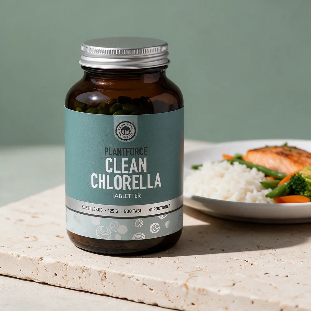 Plantforce Clean Chlorella i en brun glasskrukke med aluminiumslokk og grønnblå etikett ved en tallerken med laks, ris og grønnsaker på en travertinblokk