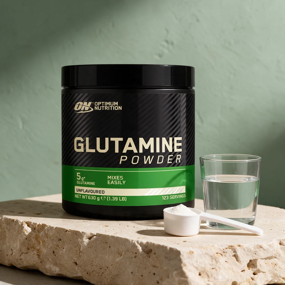 Optimum Nutrition Glutamine Powder, svart boks med grønt felt merket «Unflavoured», en hvit scoop med pulver og et vannglass