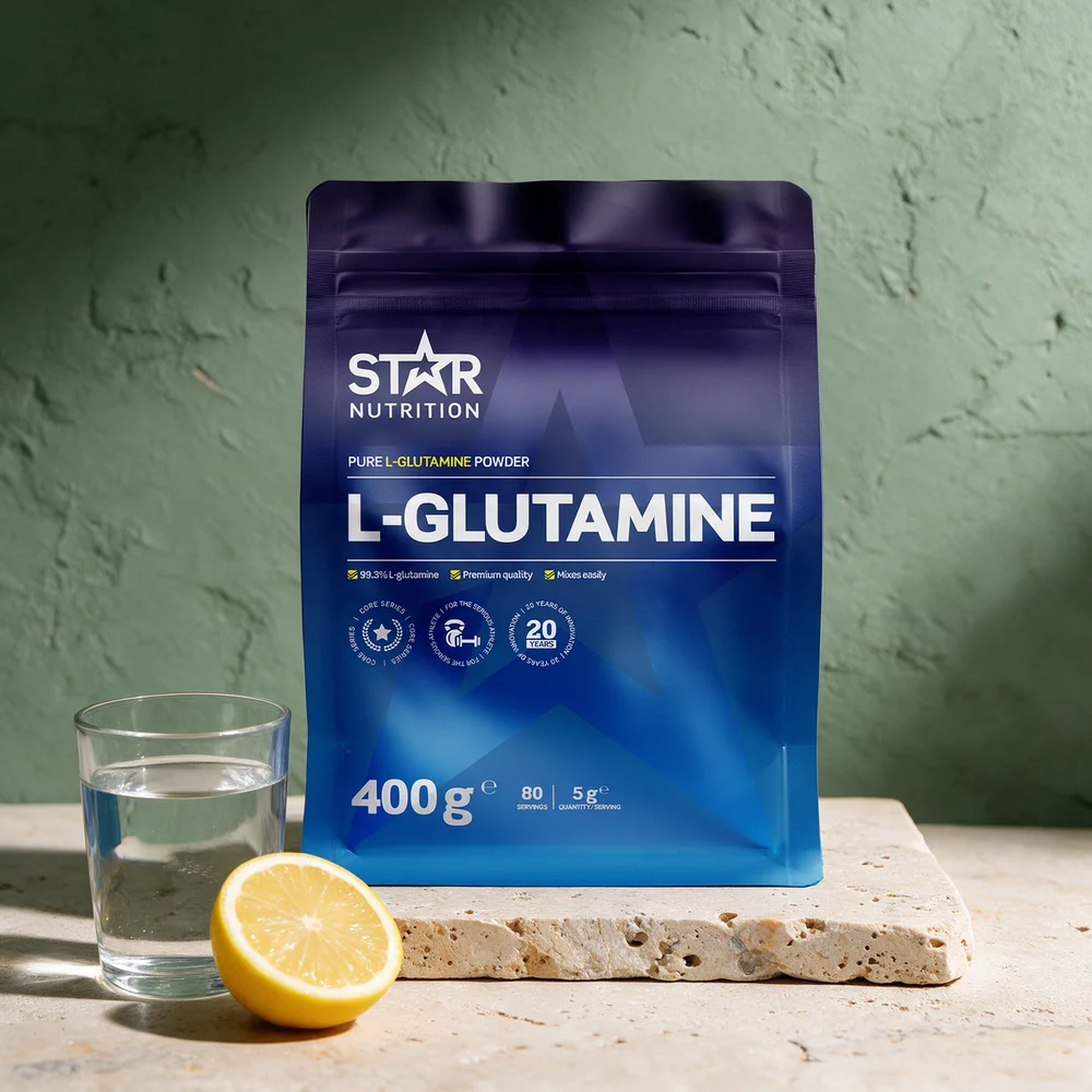 Star Nutrition L-Glutamine, blå pose på 400 g merket «99.3% L-glutamine», ved et vannglass og en halv sitron