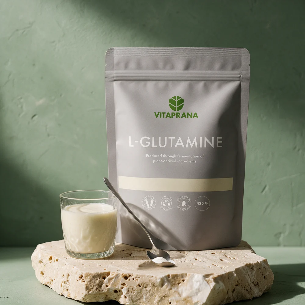 Vitaprana L-Glutamine, grå stående pose på 425 g merket «Produced through fermentation of plant-derived ingredients», med en skje pulver og et glass hvit drikk