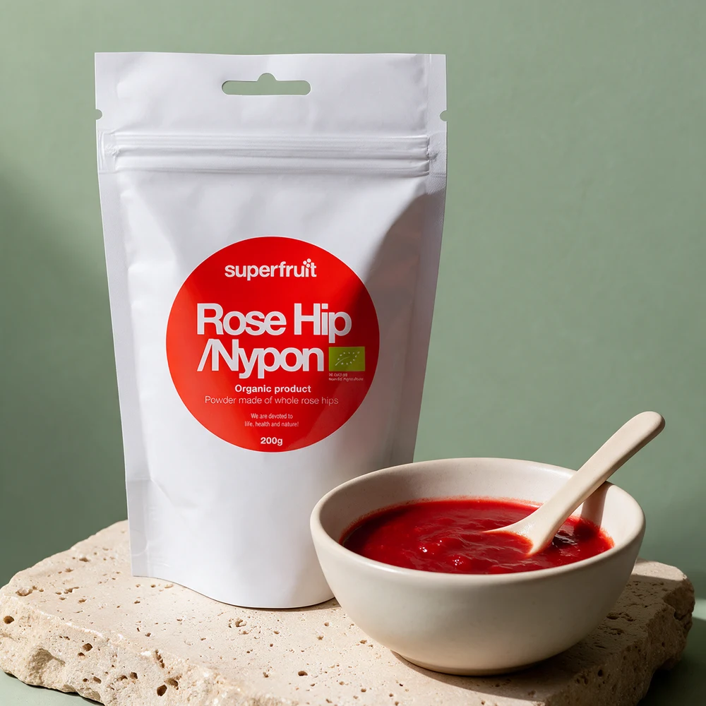 Superfruit Nypepulver, stående pose på 200 g med glidelås og rødt merke «Rose Hip / Nypon», ved en skål nypesuppe