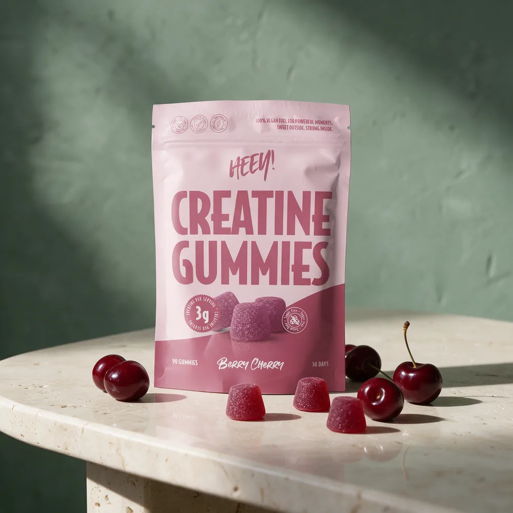 Heey! Creatine Gummies Berry Cherry i rosa, stående pose med mørkerøde gummies og kirsebær foran