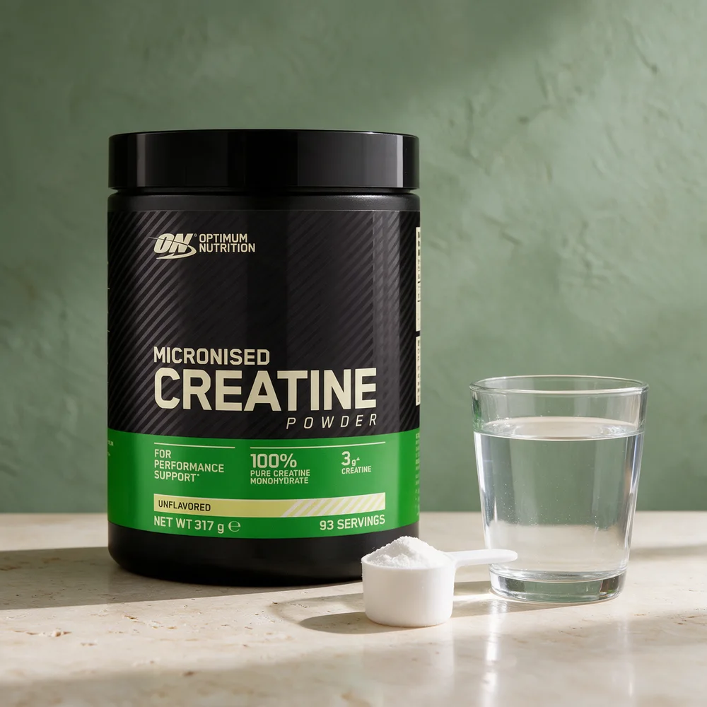 Optimum Nutrition Micronised Creatine Powder i svart boks med grønt felt, med en måleskje med pulver og et vannglass