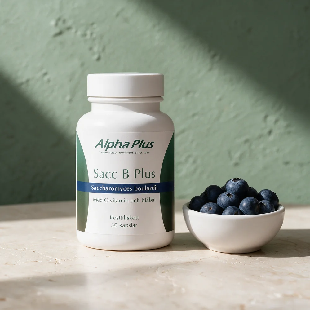 Alpha Plus Sacc B Plus, boks med 30 kapsler Saccharomyces boulardii med C-vitamin og blåbær, ved en skål blåbær