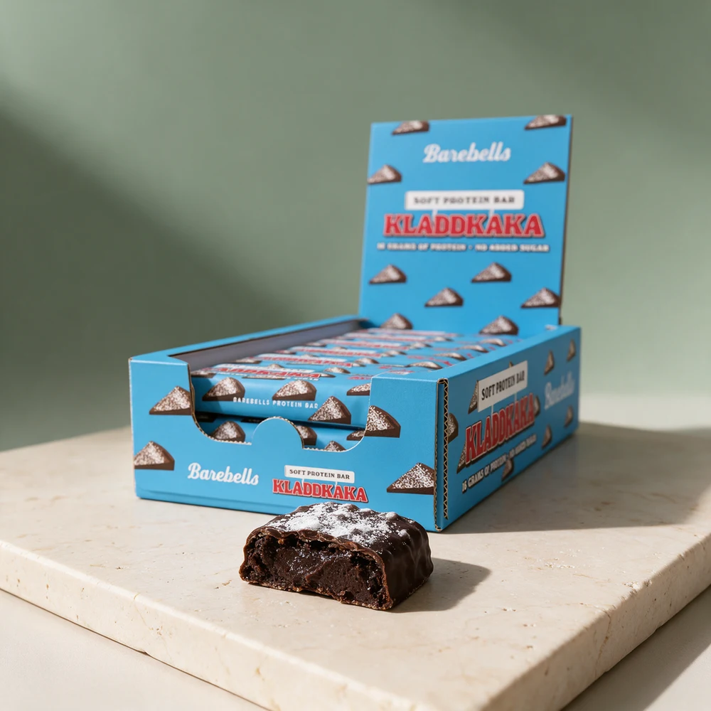 Barebells Soft Protein Bar Kladdkaka i eske og en delt bar med mørk, myk kjerne under sjokoladetrekk