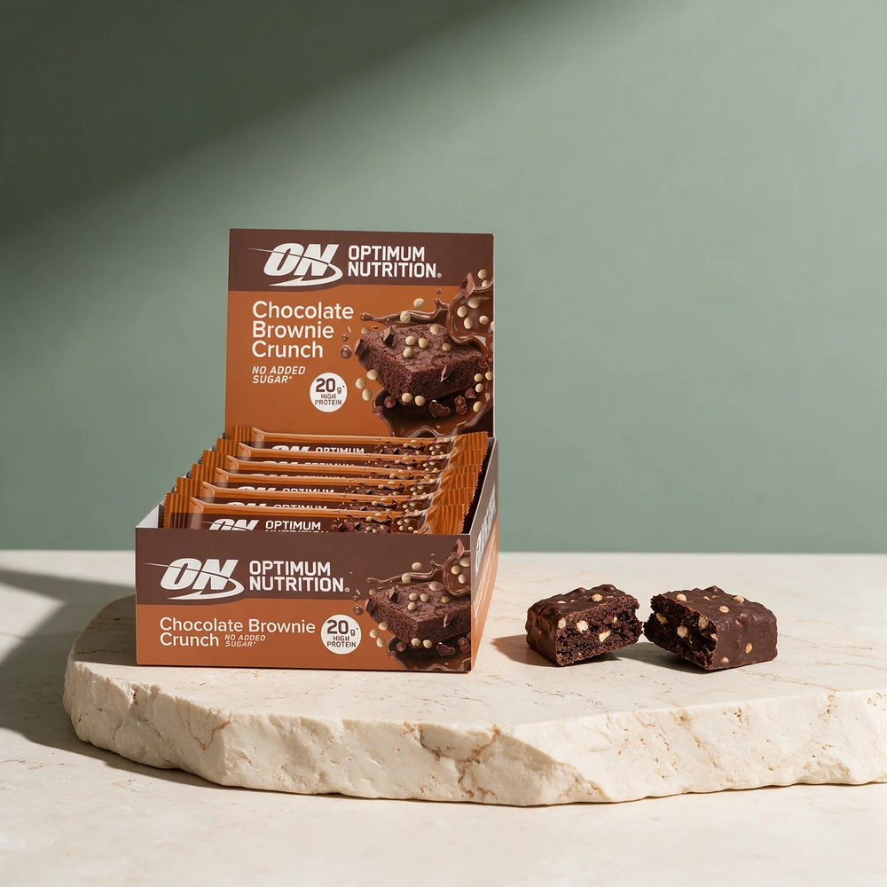 Optimum Nutrition Protein Bar Chocolate Brownie Crunch i eske og en bar brukket i to med sprø biter i massen