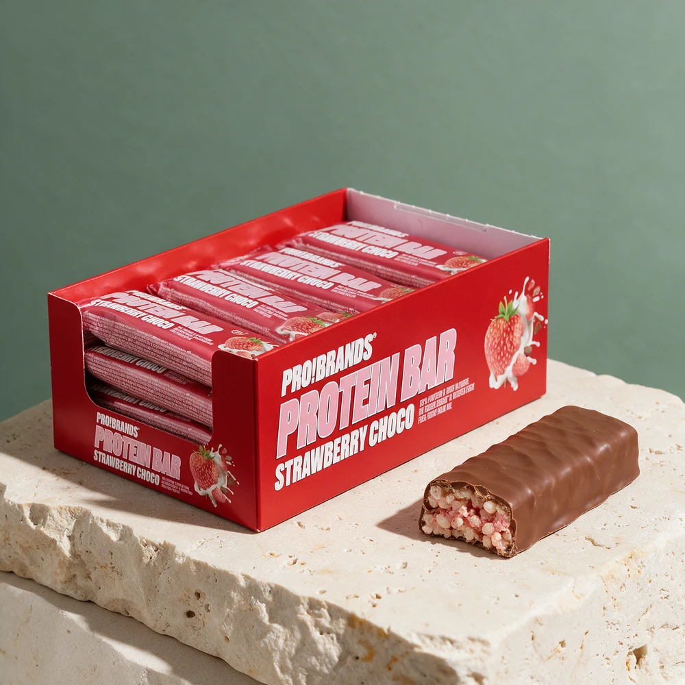 Pro Brands Protein Bar Strawberry Choco i eske og en bar med melkesjokoladetrekk, delt så riskrisp og rosa masse syns