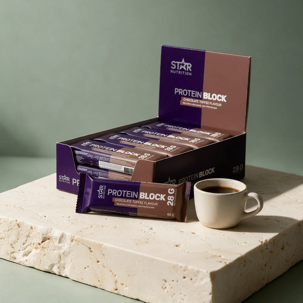 Star Nutrition Protein Block Chocolate Toffee i eske og én blokk i omslag ved siden av en liten kopp kaffe