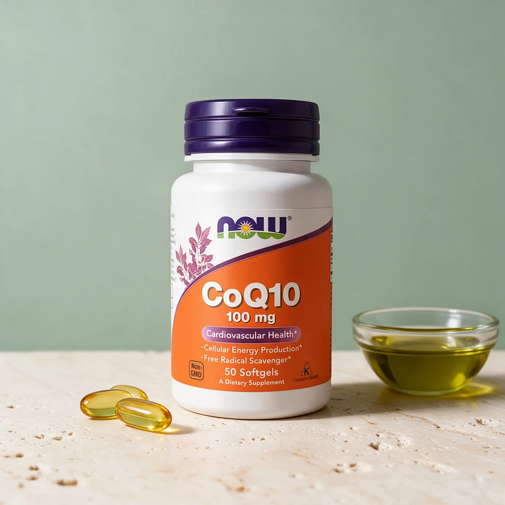 NOW CoQ10 100 mg i hvit boks, oransje etikett og lilla lokk, noen softgels foran