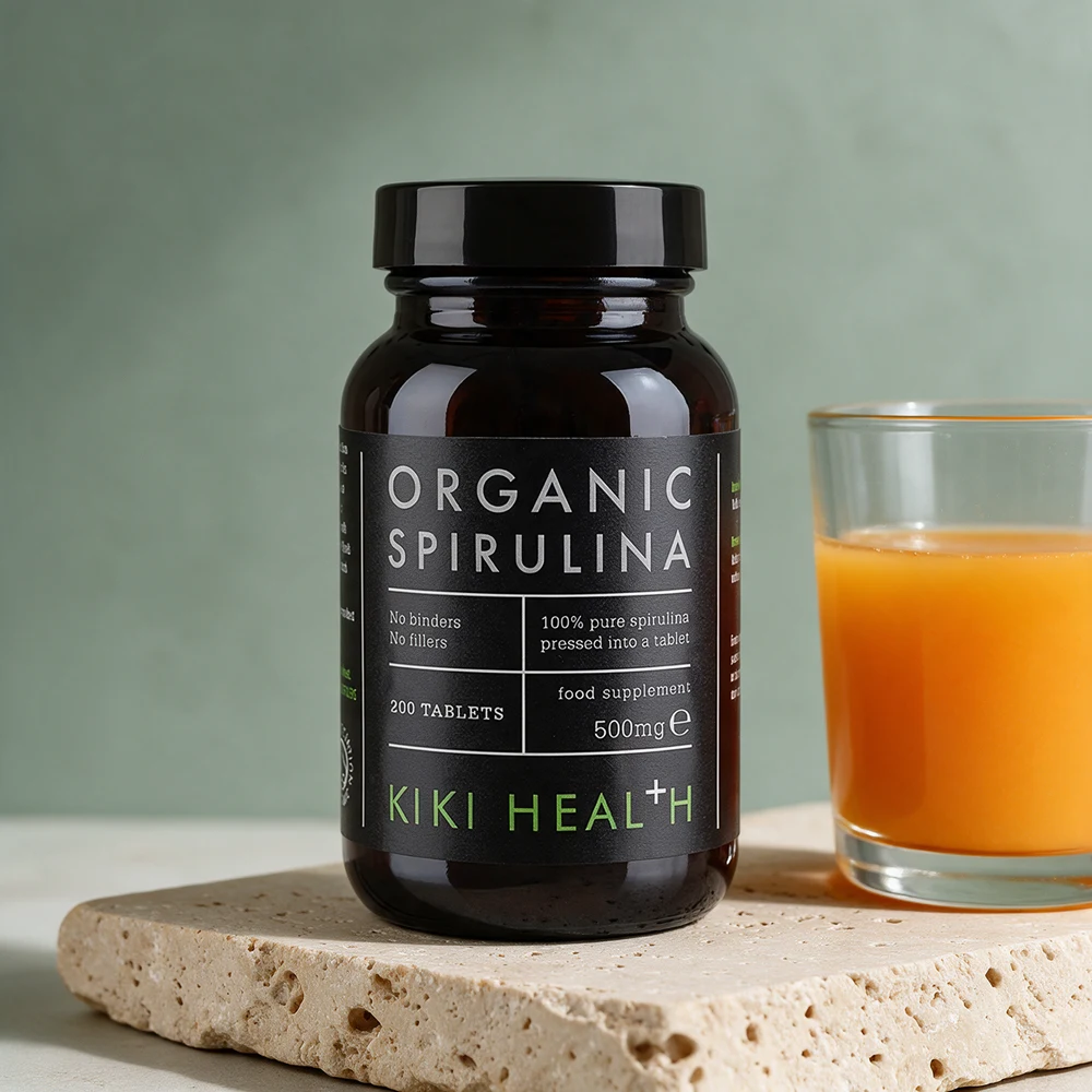 Kiki Health Organic Spirulina, mørk boks med 200 tabletter à 500 mg og et glass juice