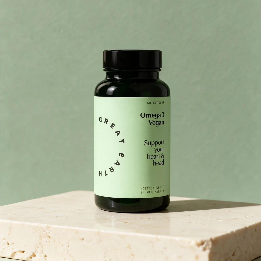 Great Earth Omega 3 Vegan i mørkegrønt glass med svart lokk og lysegrønn etikett på et travertinbord