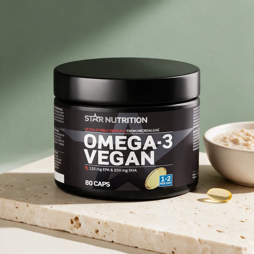Star Nutrition Ultimate Omega-3 Vegan i svart boks ved en skål grøt med en lysegul kapsel på et travertinbord