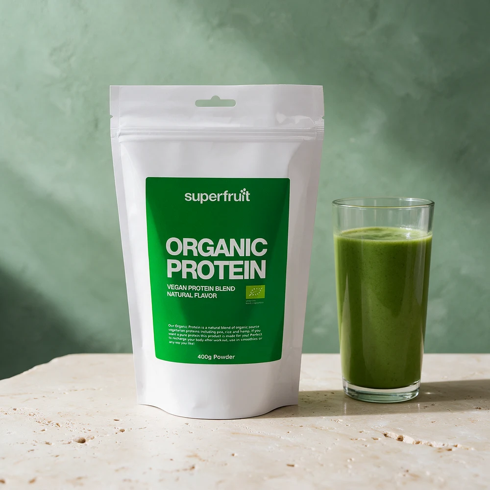 Superfruit Organic Protein i pose ved en grønn smoothie på et travertinbord