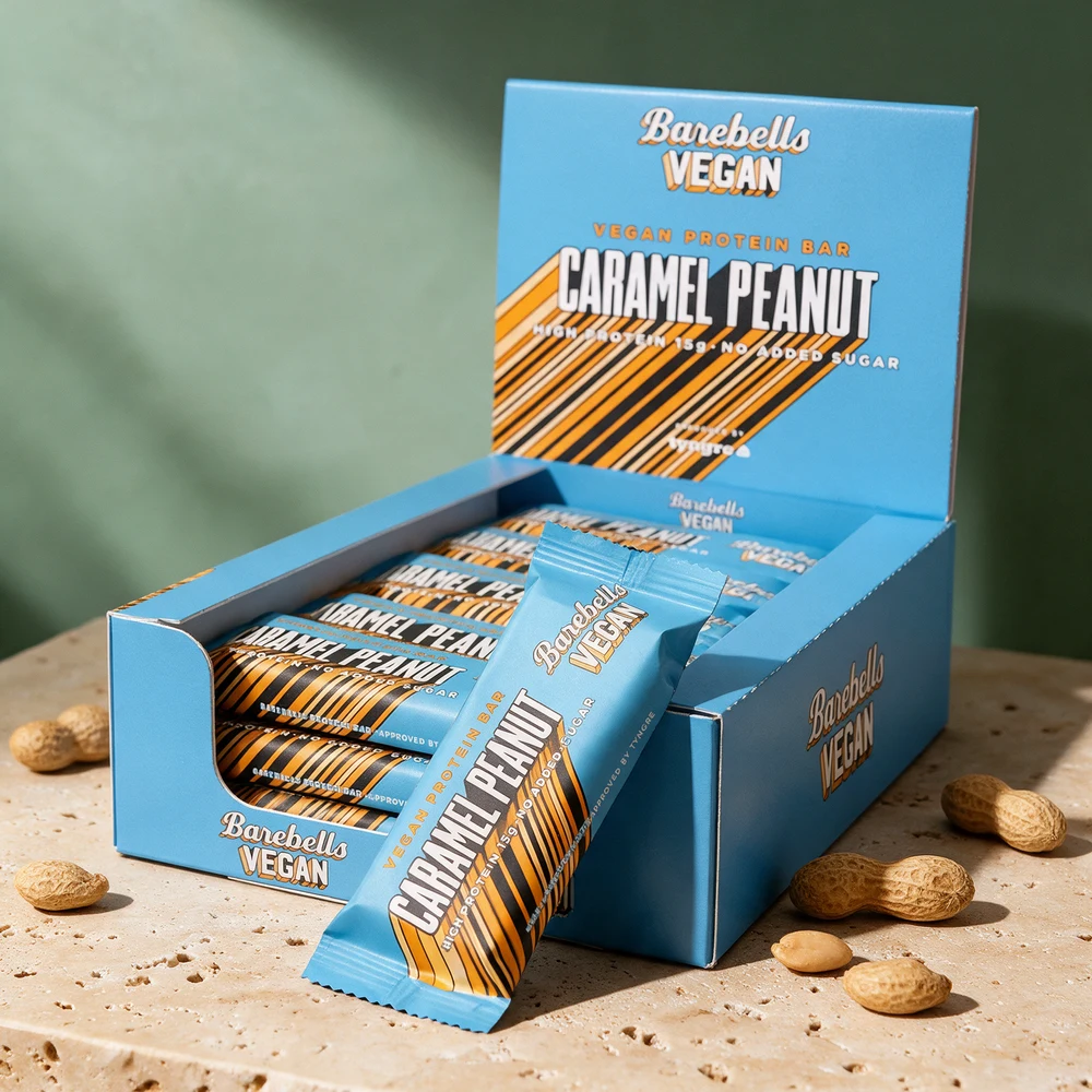 Barebells Vegan Protein Bar Caramel Peanut, tolv barer i esken og én liggende foran