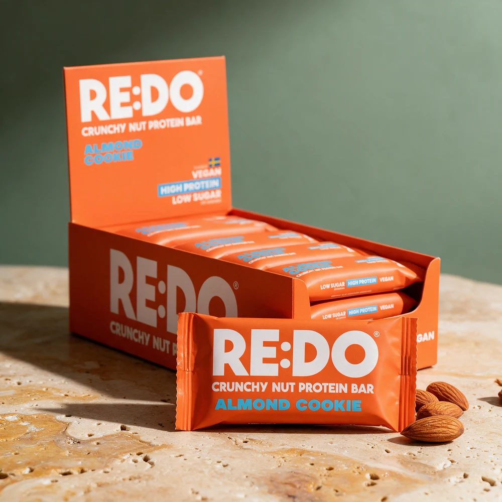 RE:DO Crunchy Nut Protein Bar Almond Cookie, femtenpakning med én bar foran
