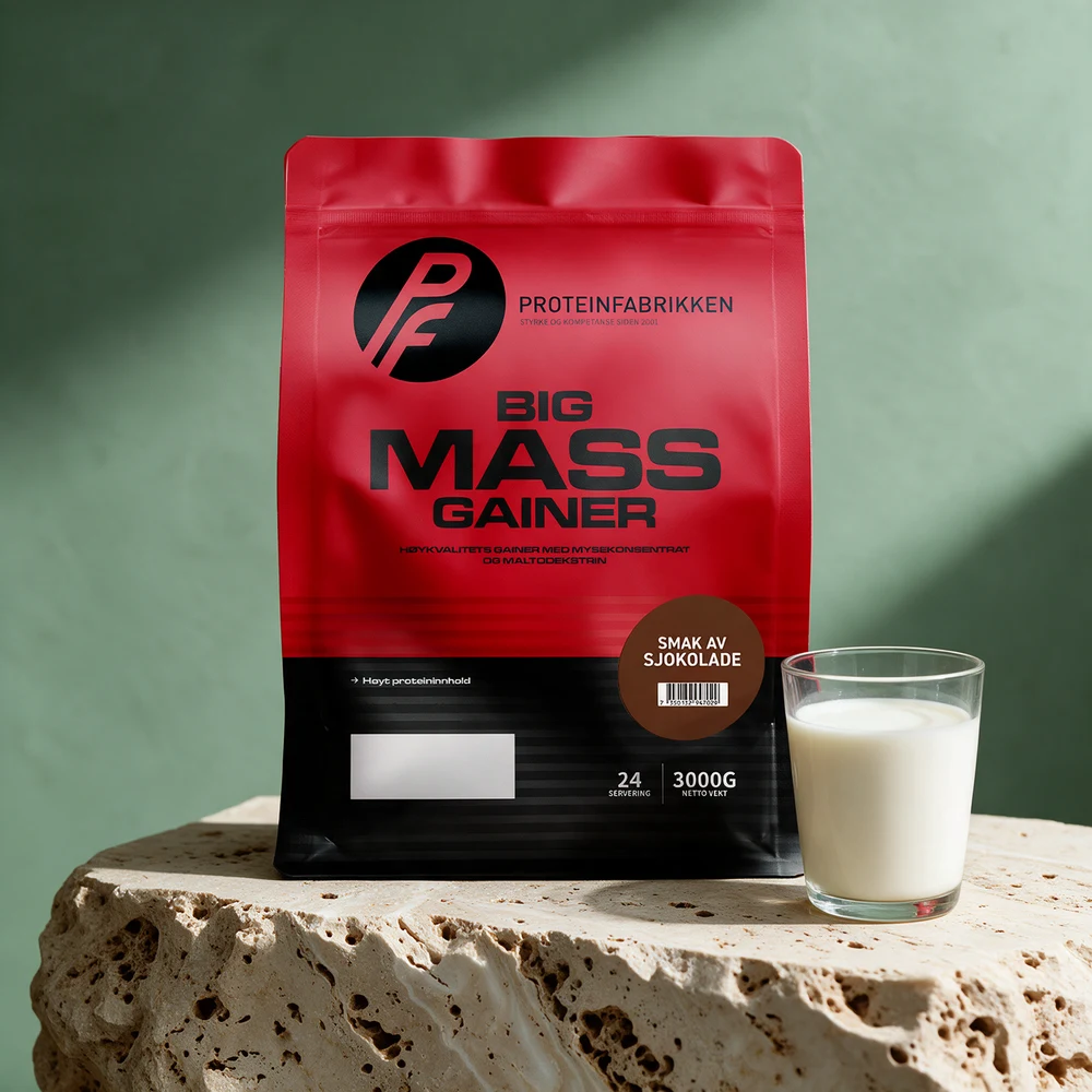 Rød og svart pose med Proteinfabrikken Big Mass Gainer sjokolade og et glass melk på et travertinbord