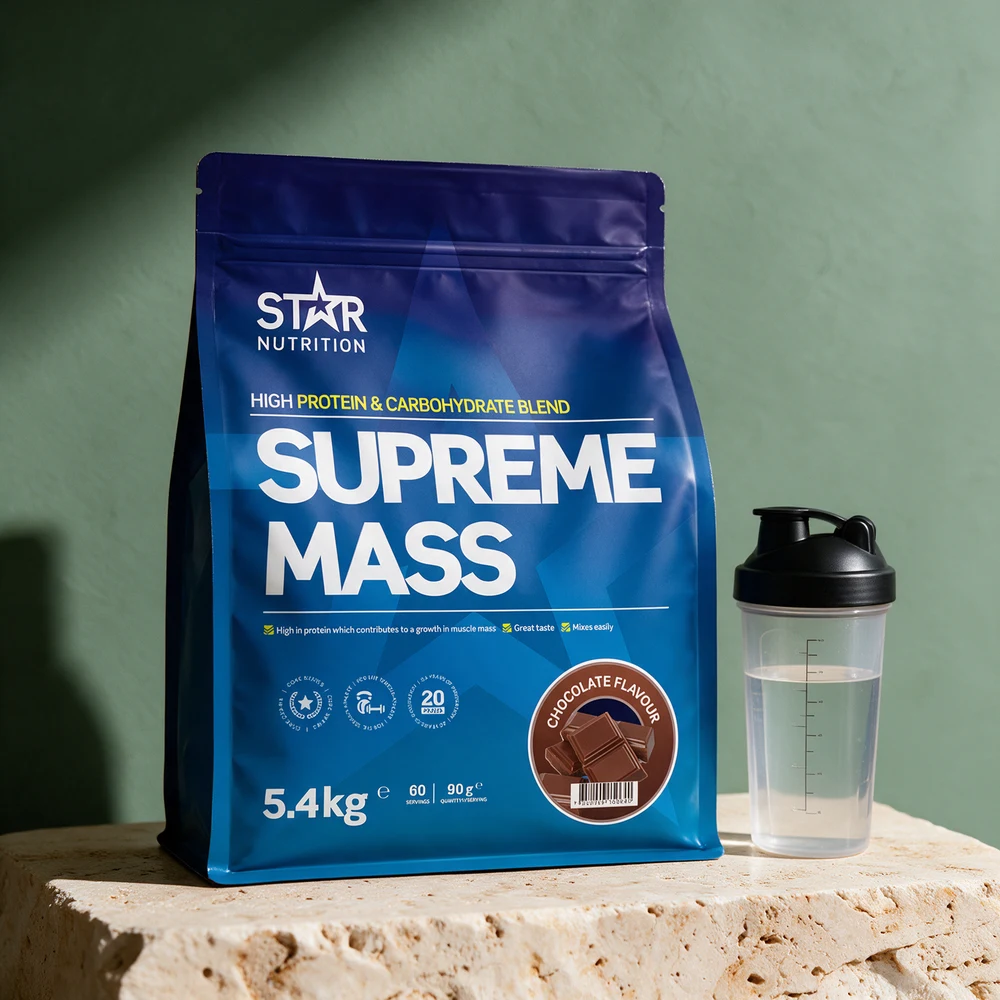 Blå pose med Star Nutrition Supreme Mass Chocolate og en shaker fylt med vann på et travertinbord