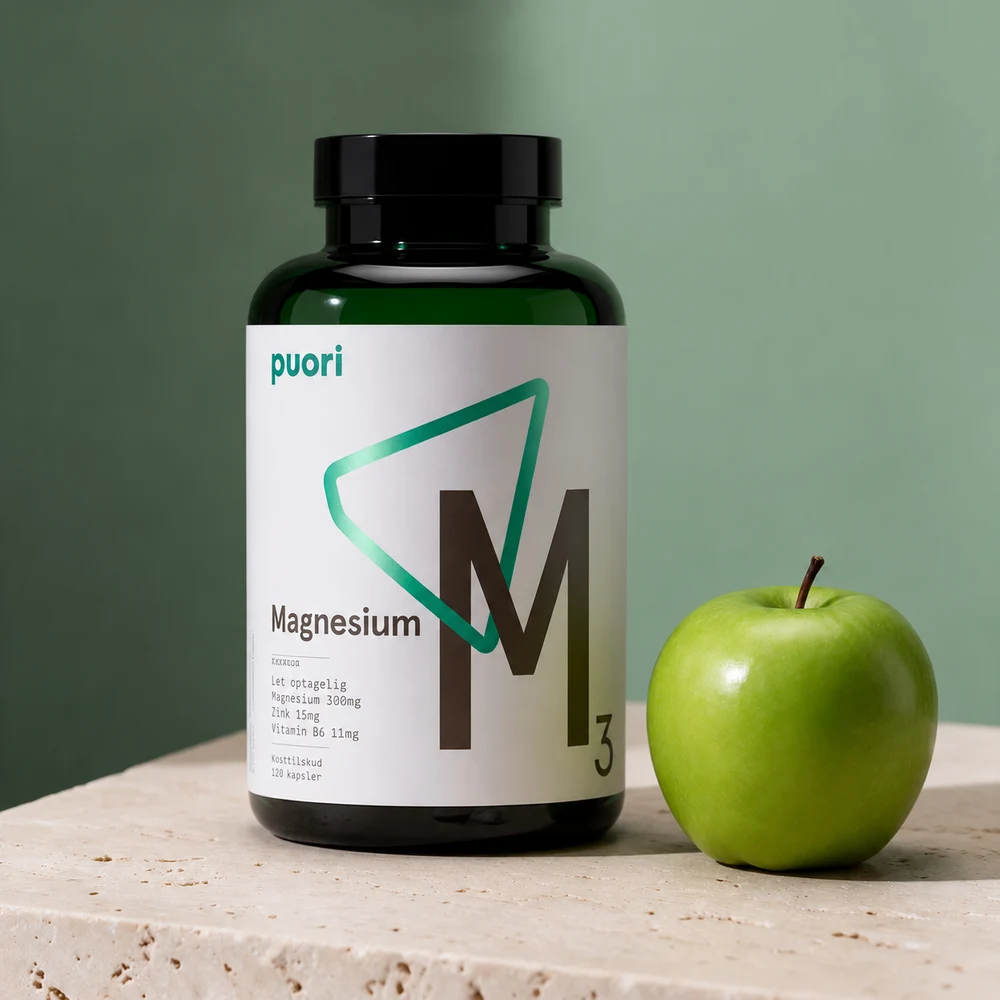 Puori M3 Magnesium & Zink i mørkegrønn glassflaske ved et grønt eple